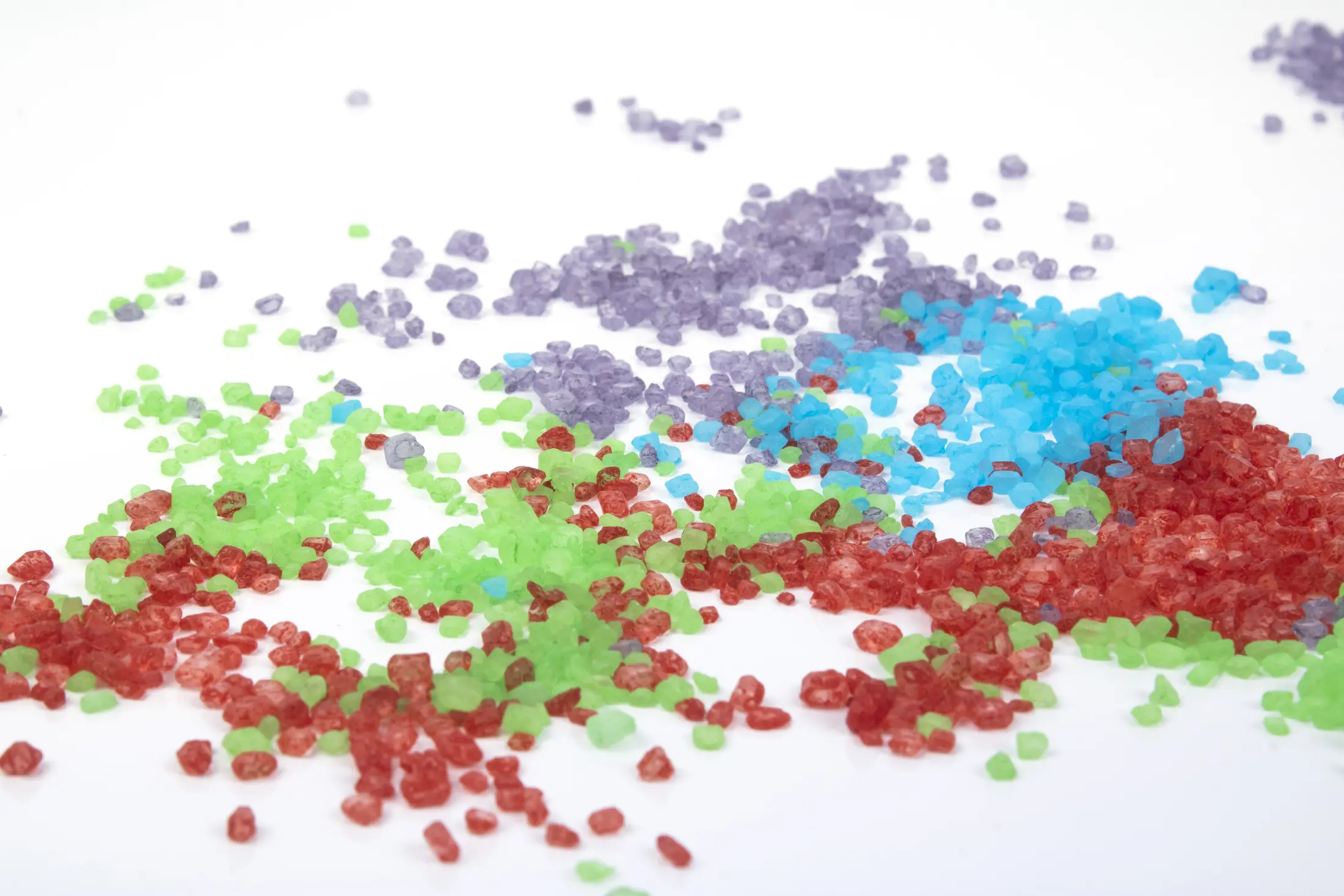 Coloured sugar crystals scattered across a white background