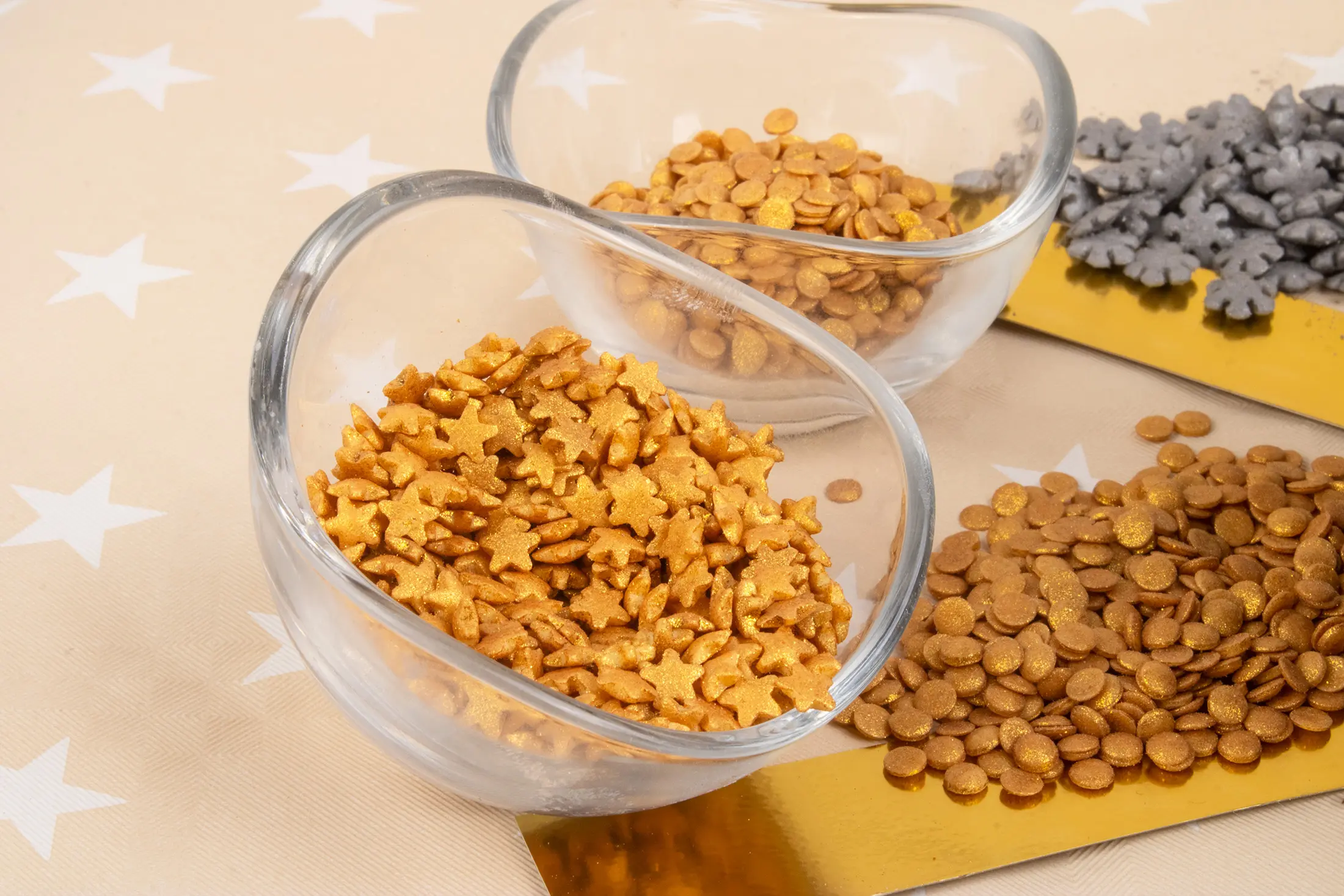 Gold stars, discs and silver decorations displayed in glass bowls