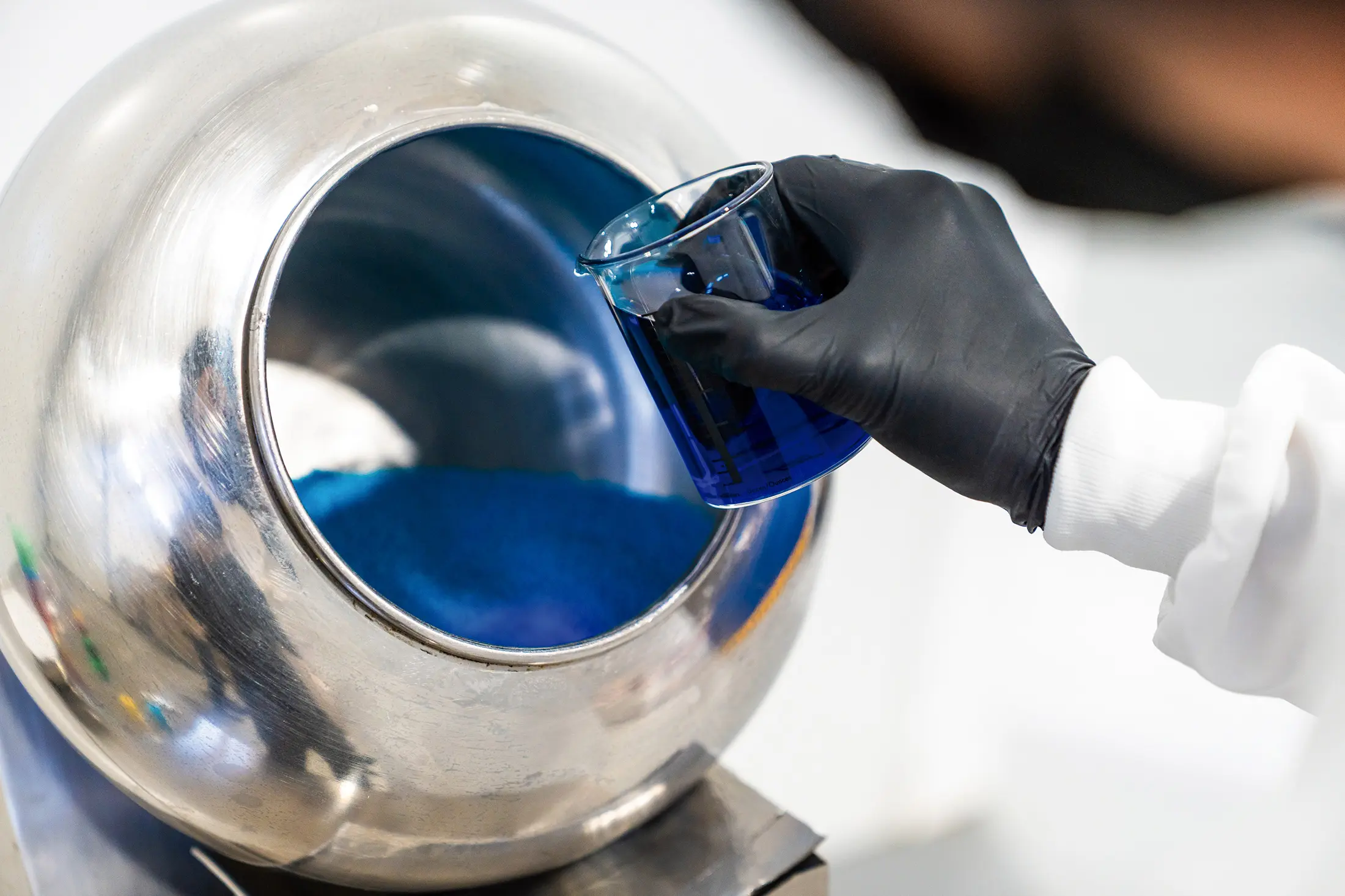 ConfetiCakes technician adding blue pigment to the production process