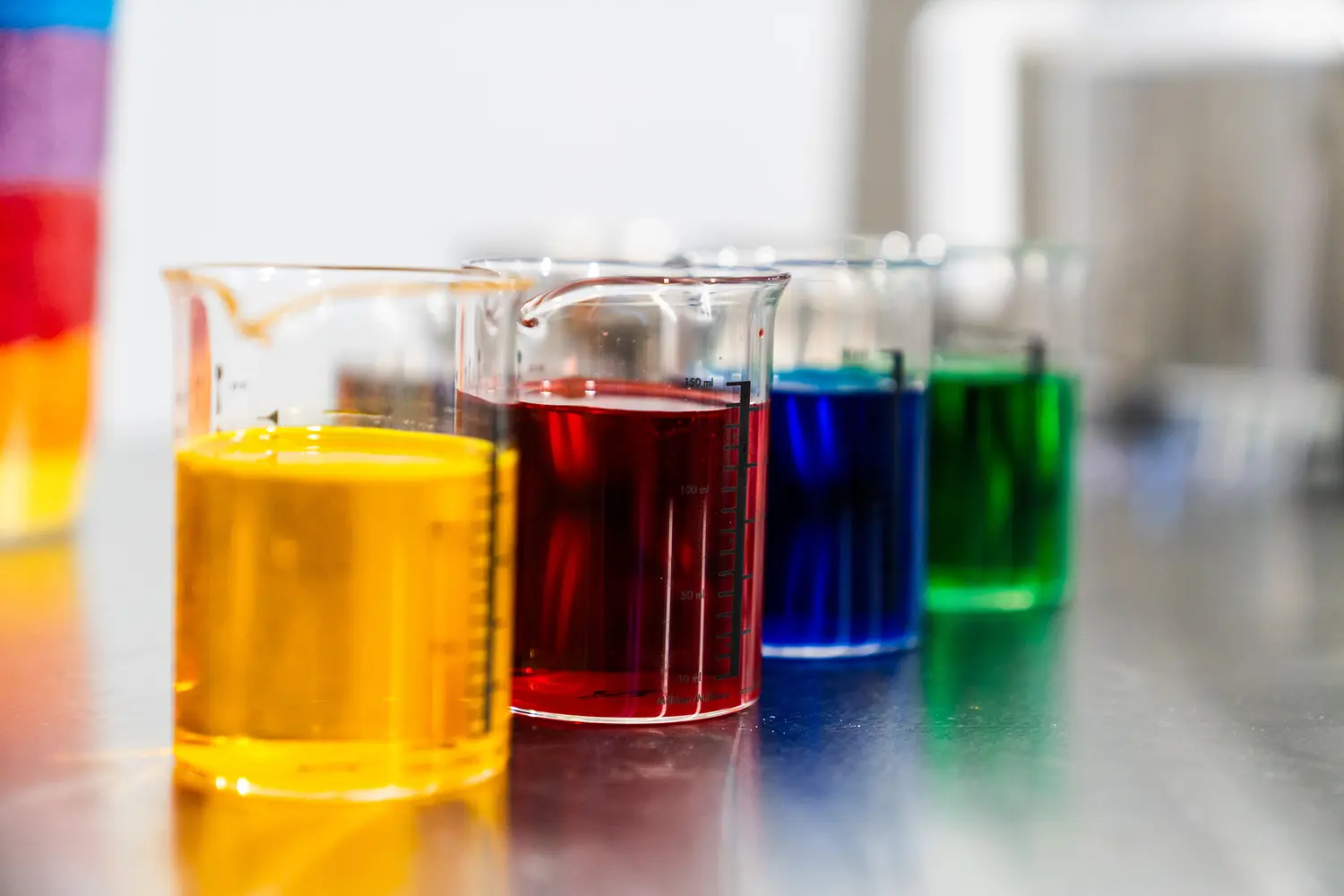 Laboratory beakers containing yellow, red, blue and green colour samples